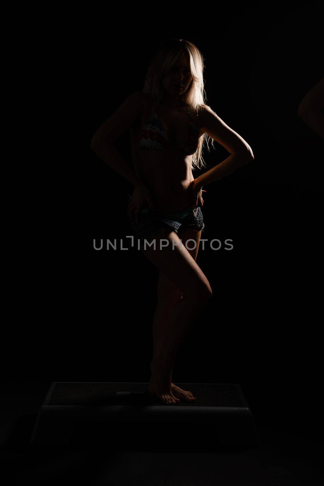 Fitness with a barbell girl blonde athlete on a black background smiles sport fit, barbell lifestyle muscles muscular slim, activity practice person sportswear strong on a black background