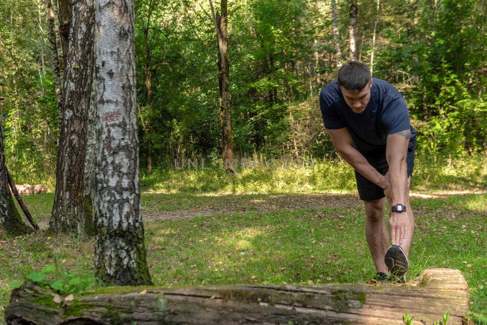 A young enduring athletic athlete is doing stretching in the forest outdoors, around the forest, oak trees.active nature, workout trail young jog, park man. energy running, runners stretches