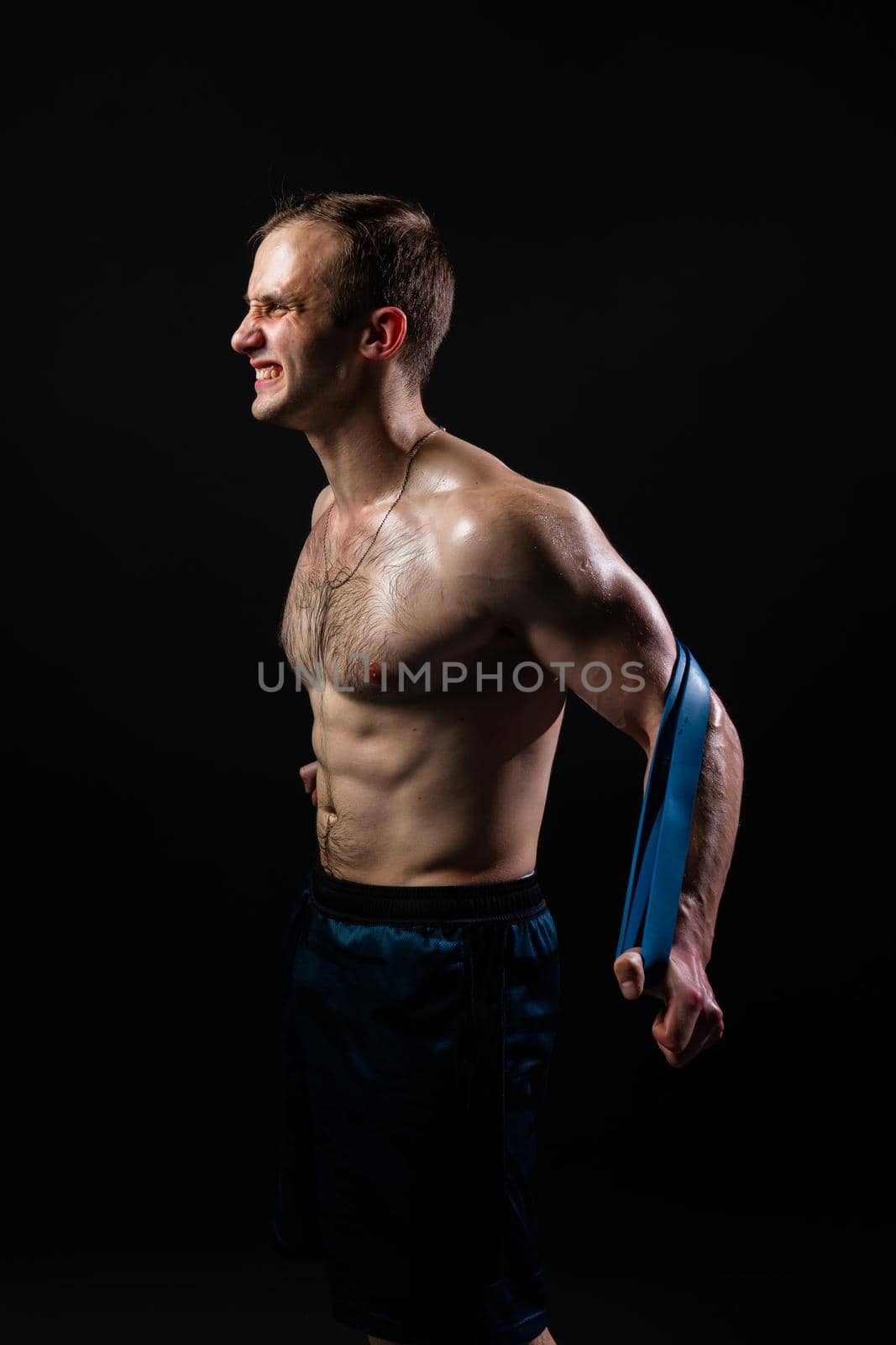 Man on black background keeps dumbbells pumped up in fitness active biceps torso, fitness bodybuilder dumbbell, shirtless pectoral. sportive adult, people fit With a ribbon in hand, the fitness gum is black