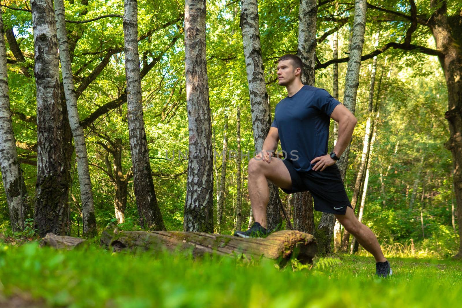A young enduring athletic athlete is doing stretching in the forest outdoors, around the forest, oak trees.active jogger fit person jog, park outside. Autumn energy running, distance stretches