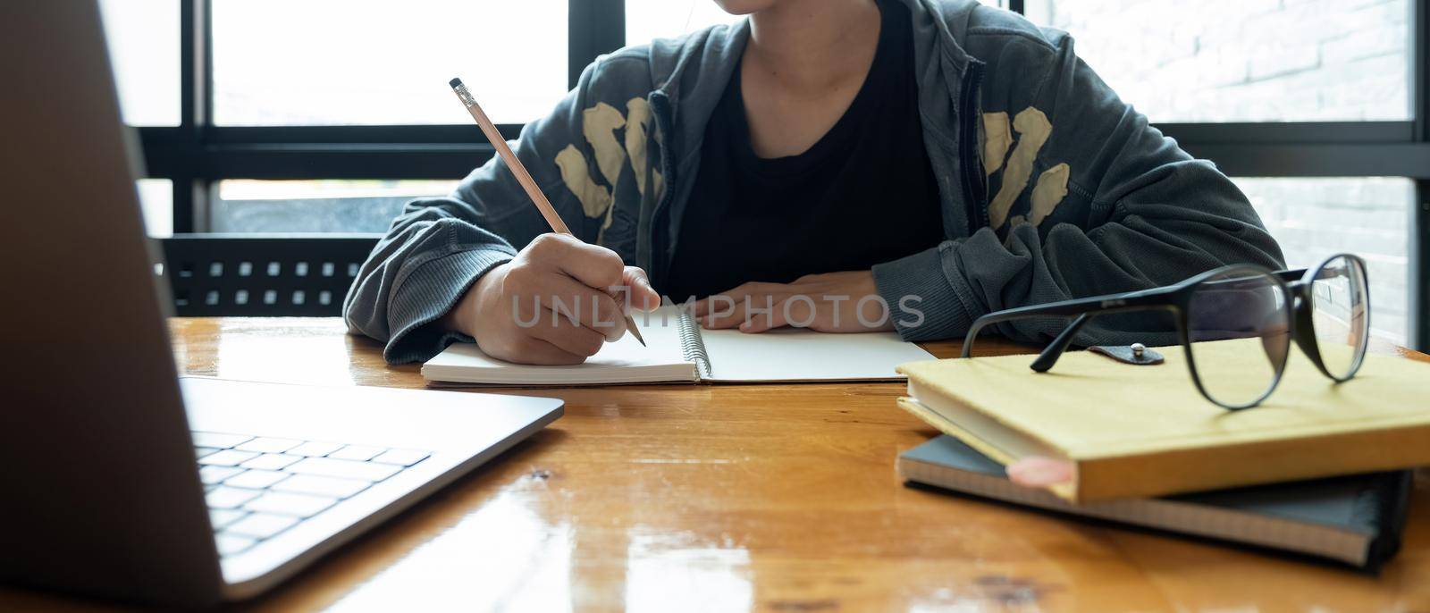 Cropped photo of asian woman writing making list taking notes in notepad working or learning on laptop indoors- educational course or training, seminar, education online concept.