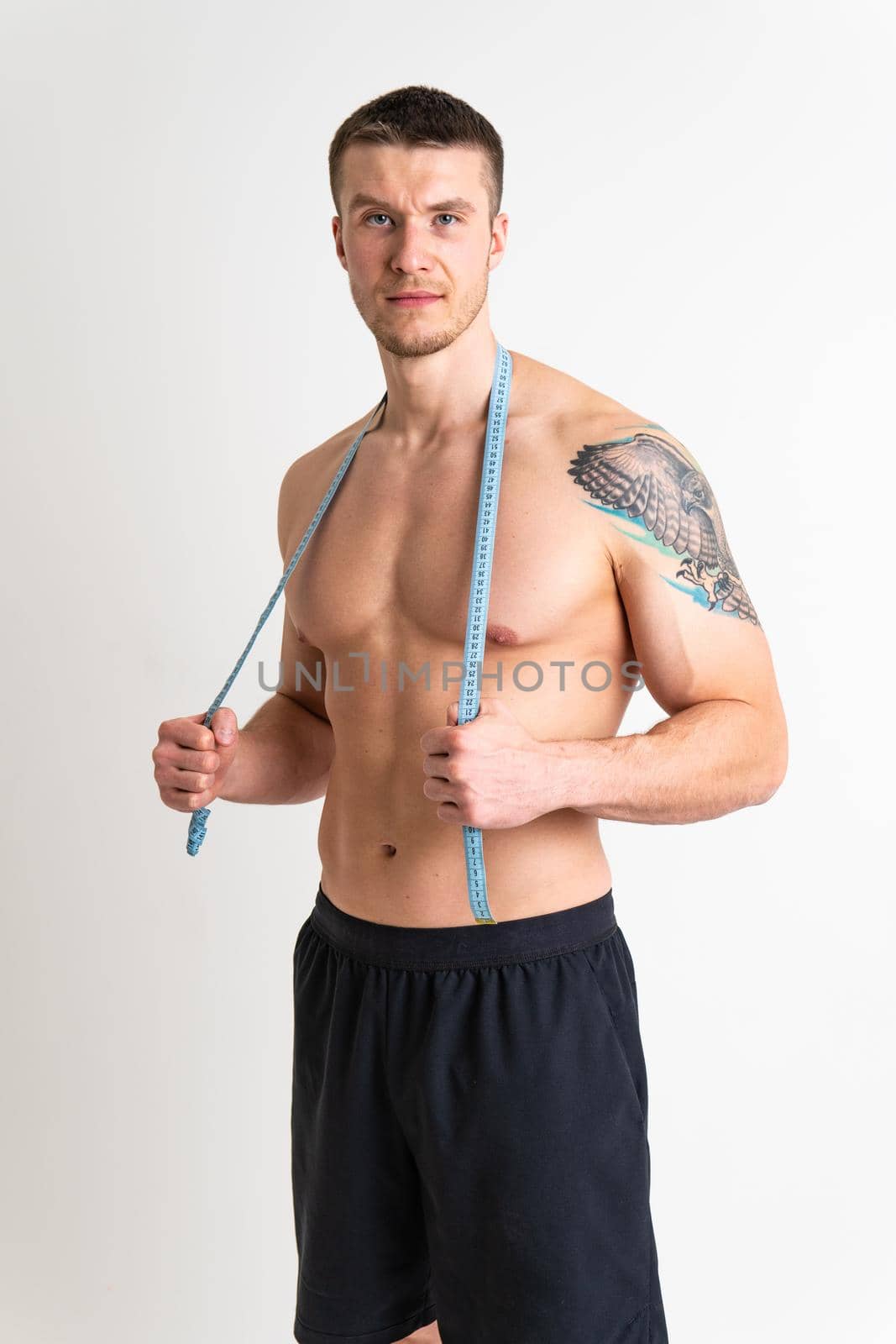 A man measures the waist of a metre and poses against a white background isolated sexy beauty, human. Weight beautiful sports, one sport attractive tape