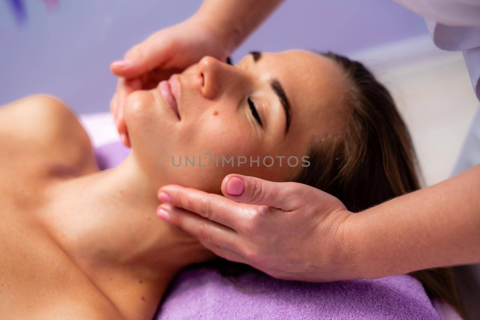 Relaxing massage. European woman getting facial massage in spa salon, side view by Matiunina
