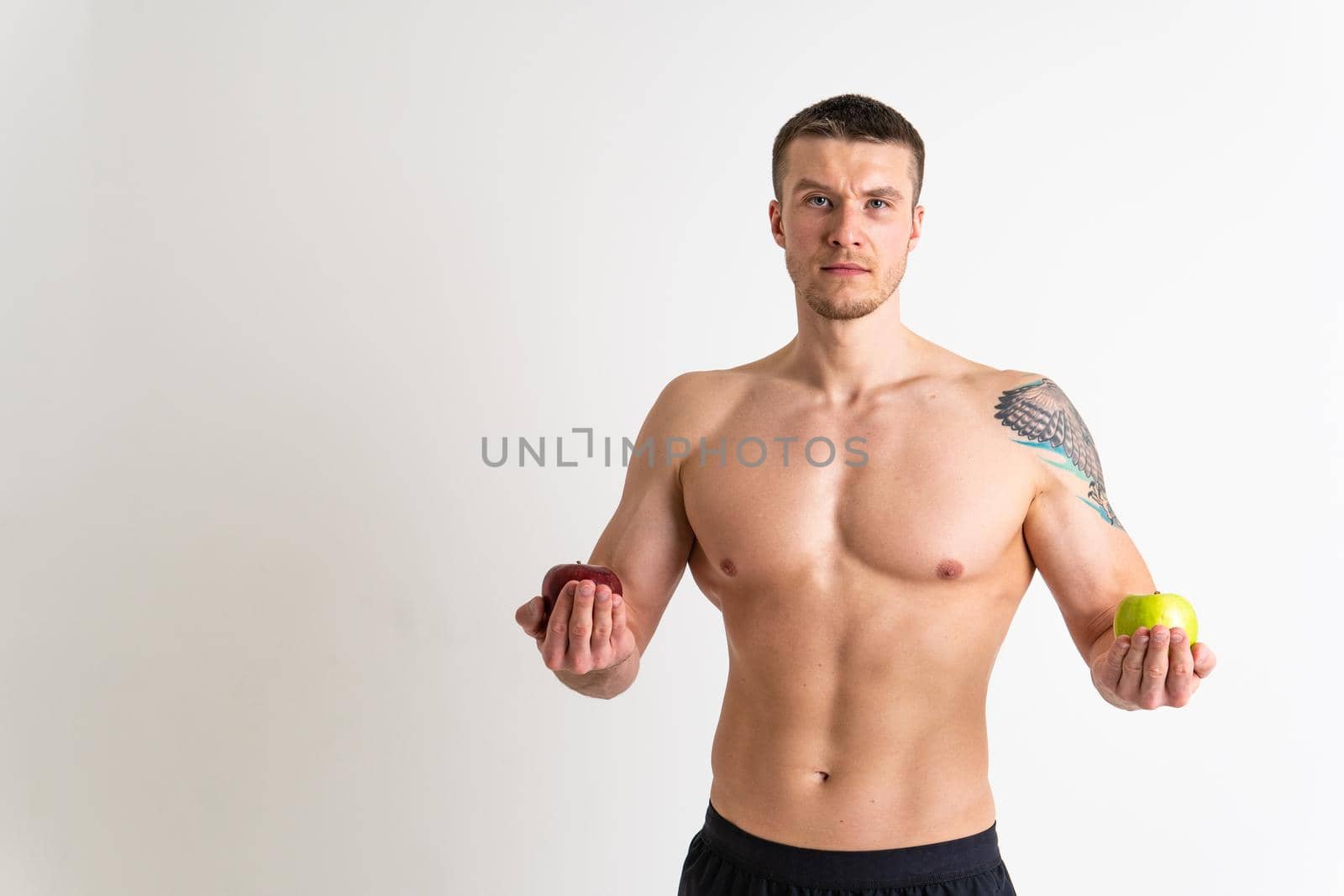 Man holds apples in fitness white background isolated apple fit fitness, muscular diet sport strong athlete, torso person. Guy vegetarian, bodybuilder chest