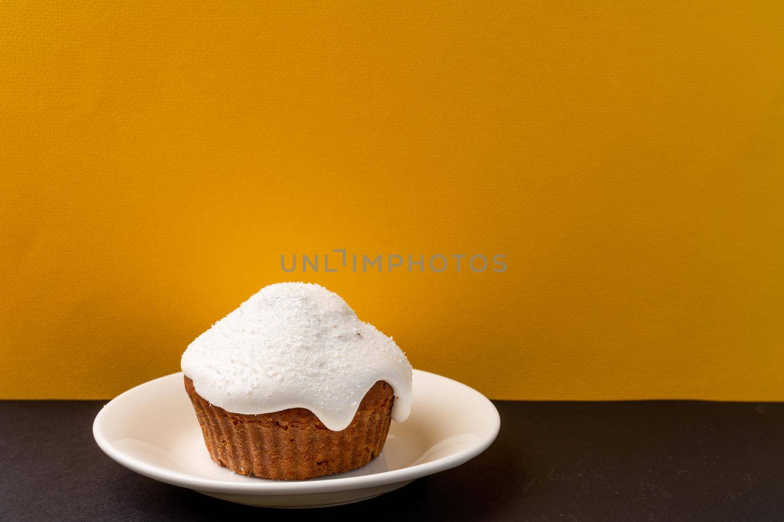 Kulich at home. Getting ready for Easter at home. Easter cake, decorated with icing, are on a yellow background