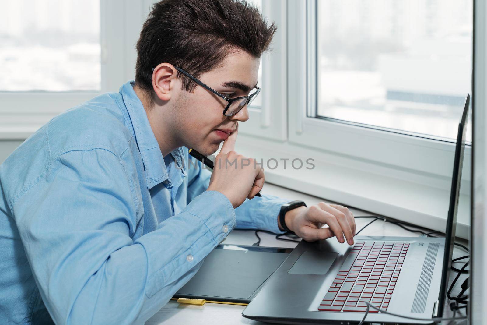 serious young man in glasses as he works on his laptop by Lena_Ogurtsova