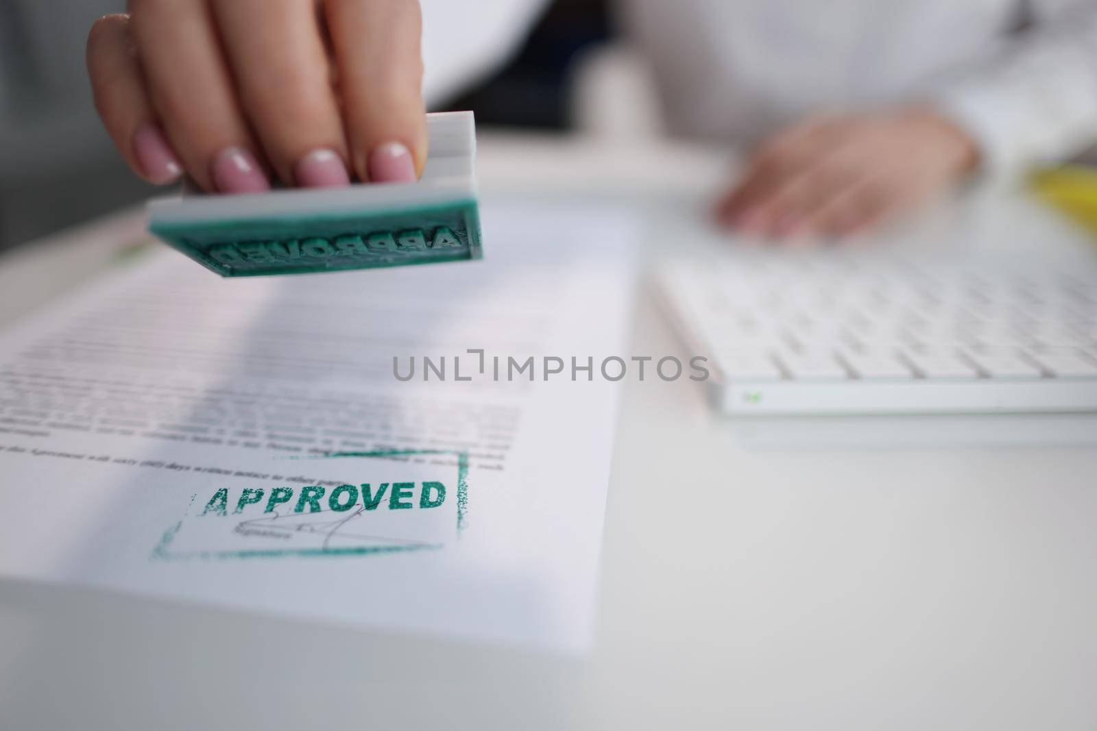Close-up of green approved stamp on document, certificate contract, agreement, lawyer hand stamping approved on sheet. Business, permit, authority concept