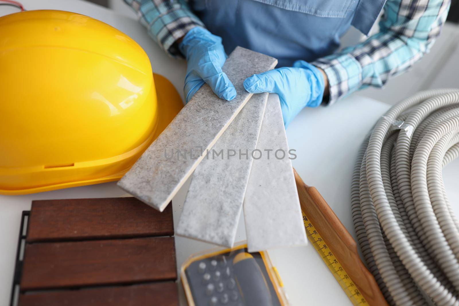 Close-up of builder hold grey tiles samples for bathroom in workshop, foreman choose perfect shade. Renovation project, construction site, interior concept