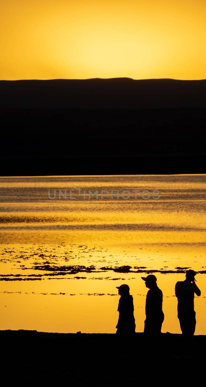 High contrast dark scene of tourist at orange sunset near lake with text space