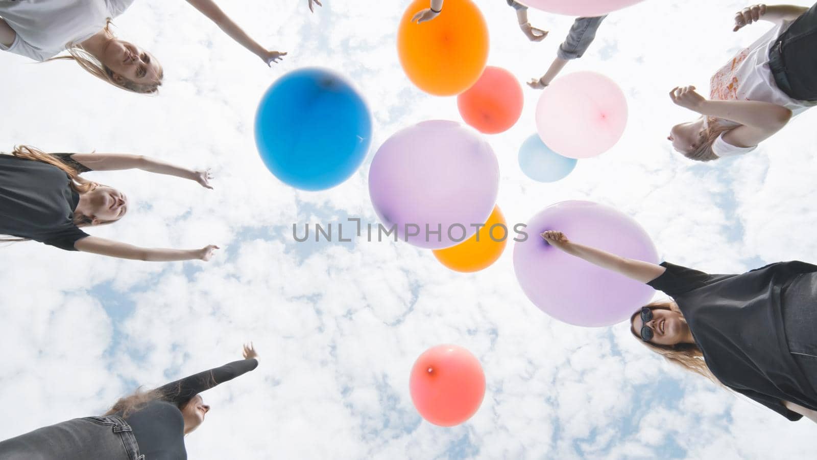 Cheerful girlfriends connect large colorful balls in a circle