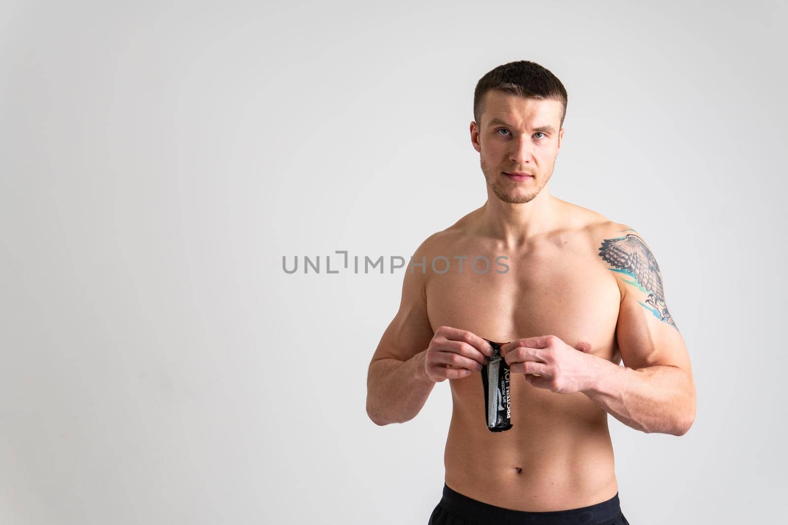 Man eats protein bar on white background isolated bar eating athlete smiling lifestyle, woman handsome. People ABS, smile female