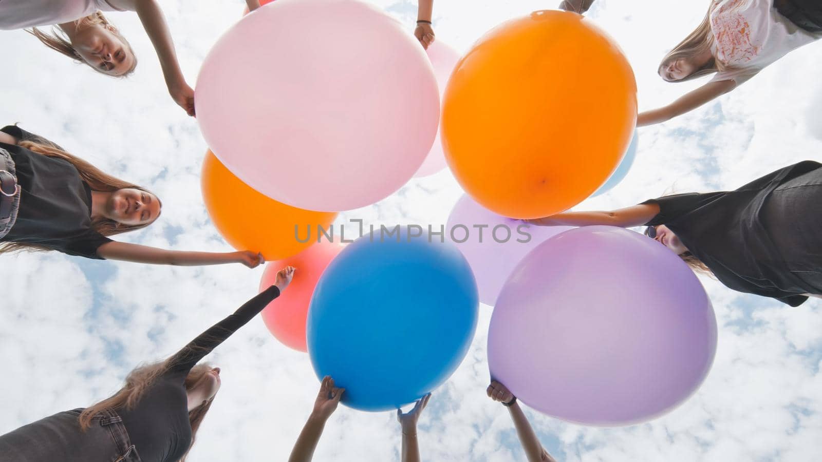 Friendly girls connect big balloons together in the park