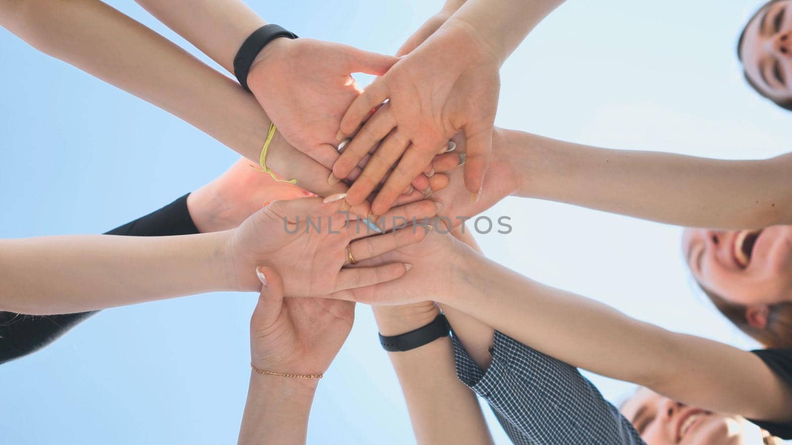 Cheerful girls join hands together as a sign of unity and joint successful work. Teamwork stacking hand concept