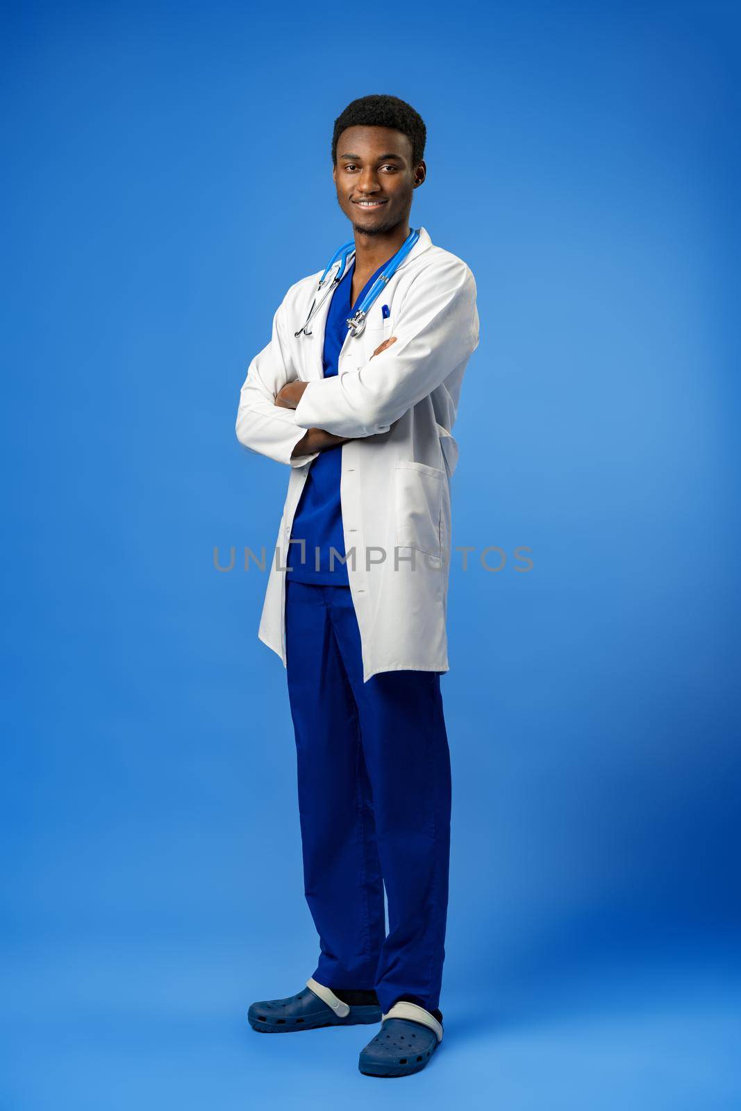 Confident black doctor posing over blue studio background, portrait