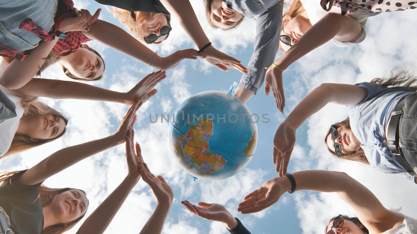 Earth conservation concept. 11 girls surround the rotating earth globe with their palms hands