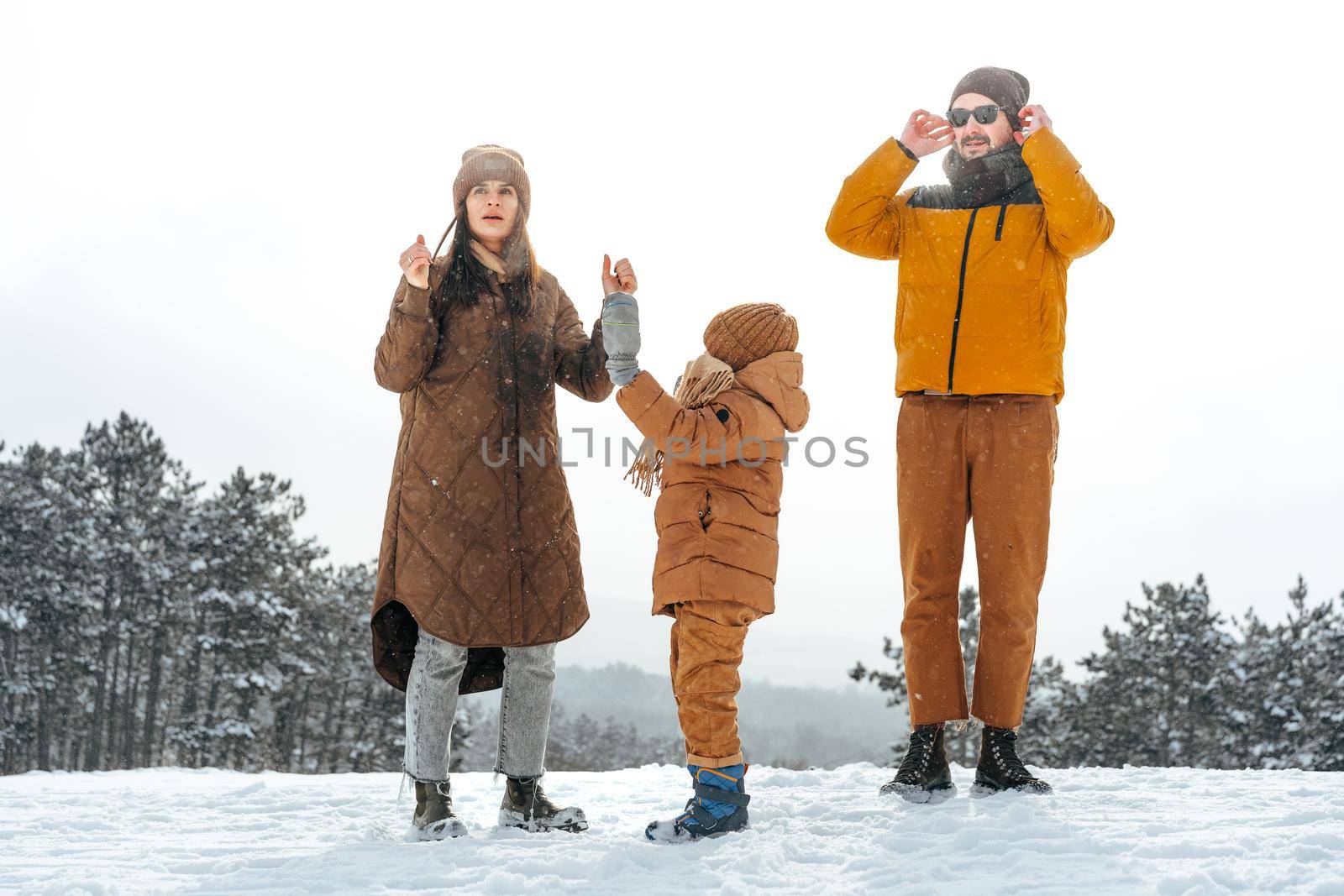 Happy family having a walk in winter outdoors in snow forest