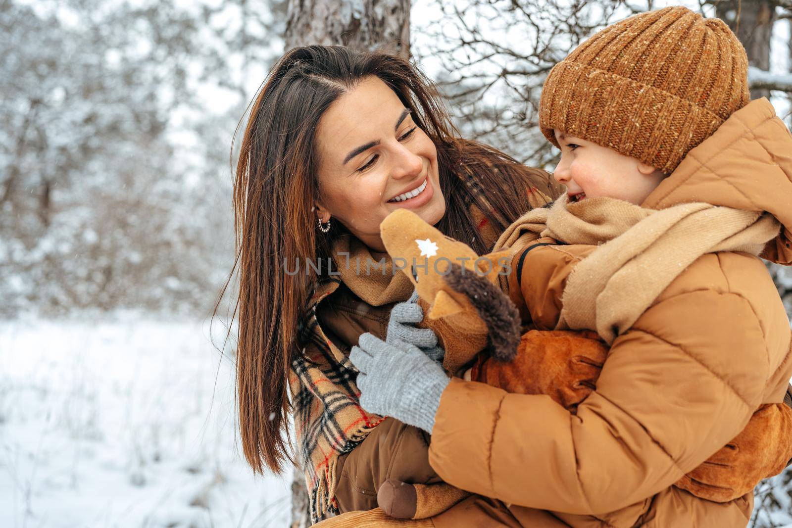 Woman with a little son on a winter hike in the snowy forest together