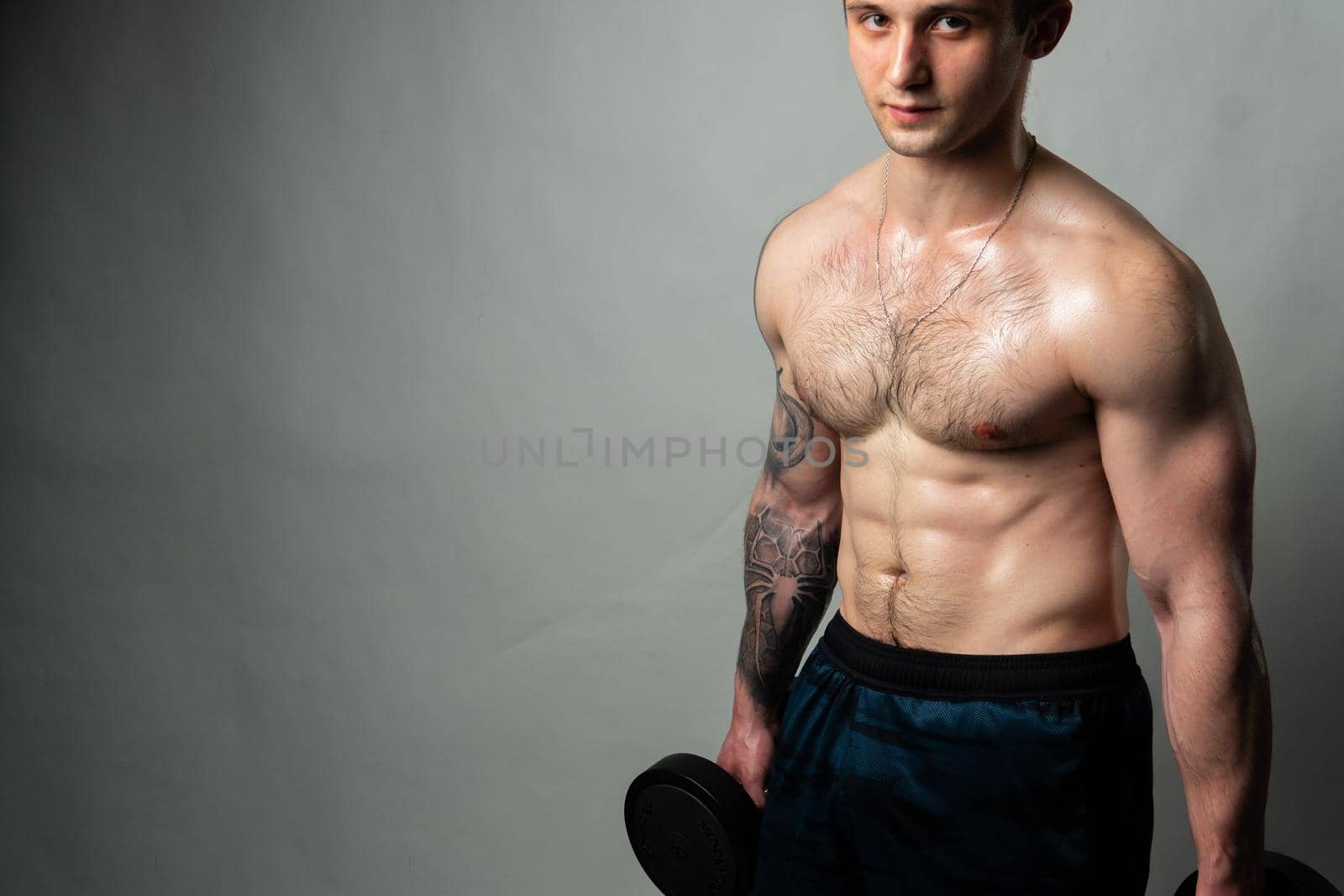 Man on black background keeps dumbbells pumped up in fitness biceps black, body training exercise heavy, shirtless weightlifting. Attractive skin adult, human fit dumbbells and body press beautiful on a white background