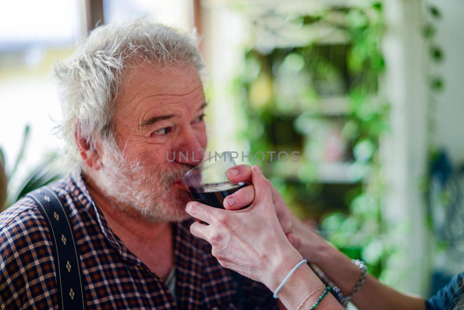 caucasian man drinking red wine and getting drunk at home stressing younger hispanic womancaregiver adn wife - alcoholism and domestic violence concept. High quality photo