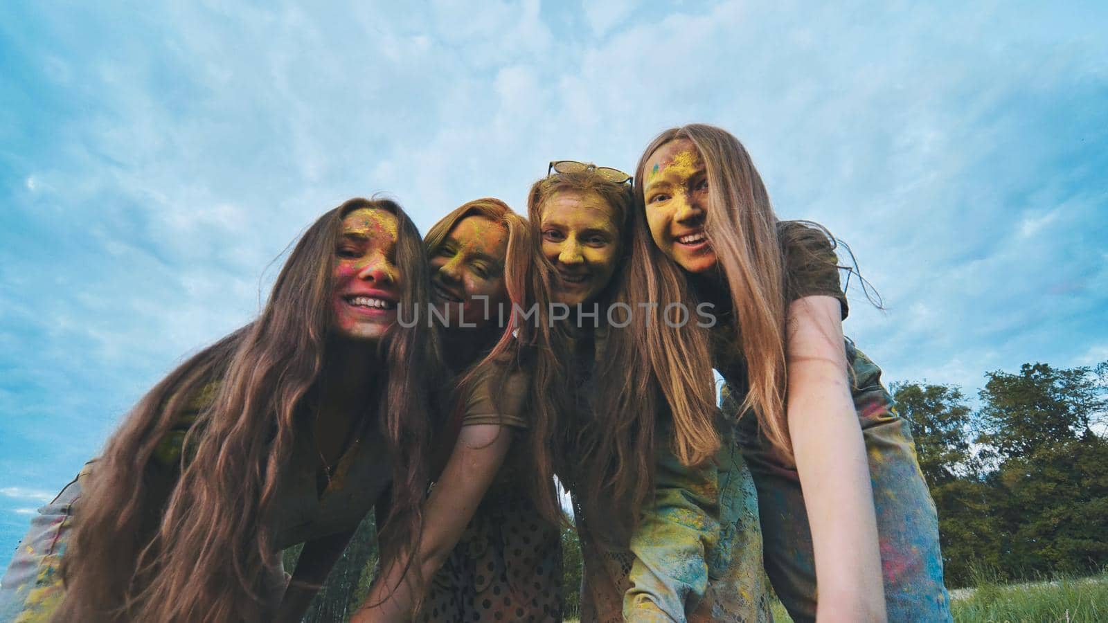 Cheerful girls are posing smeared in multi-colored powder