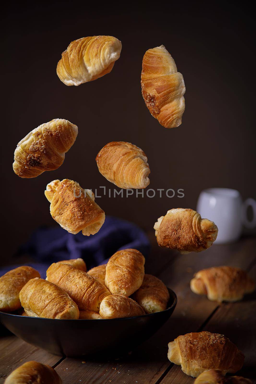 Fresh croissants fly into the plate in different positions. Levitation.