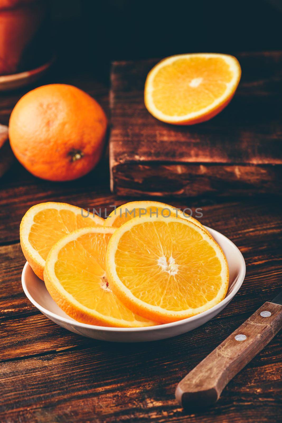 Slices of orange on white plate in rustic setting