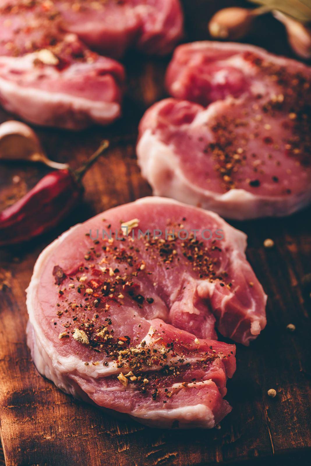 Pork loin steaks with ground spices on rustic cutting board