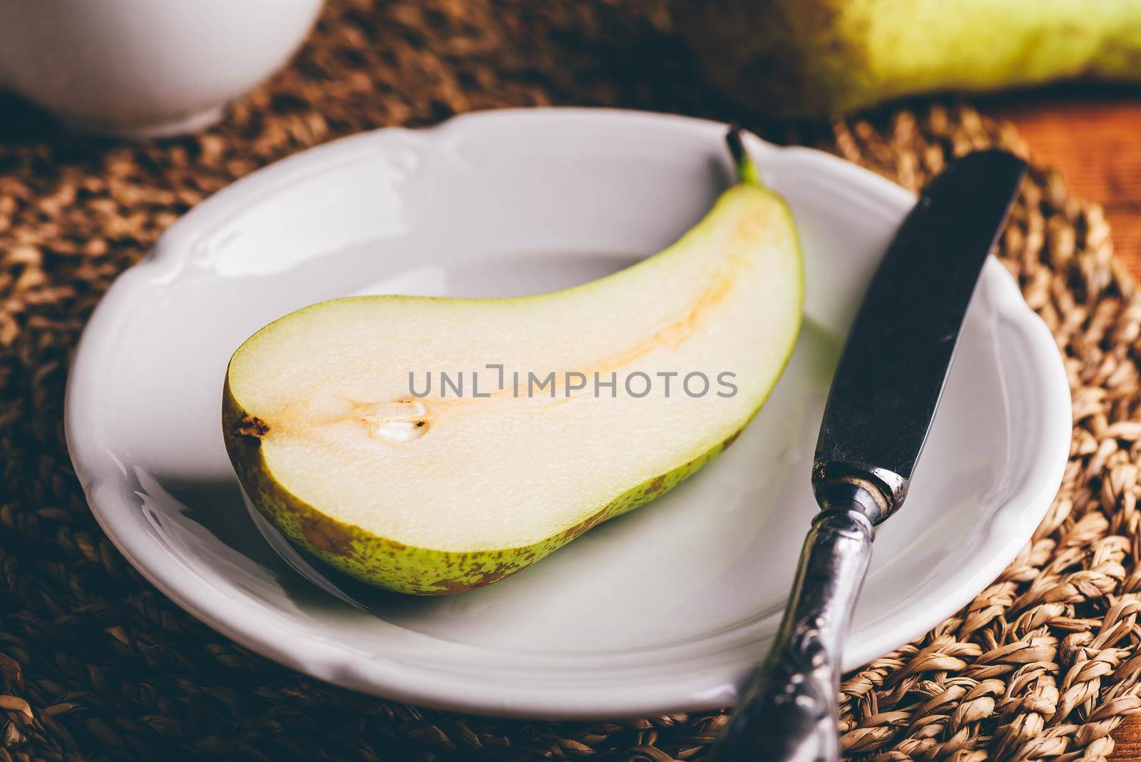 Half of Conference Pear on White Plate with Knife