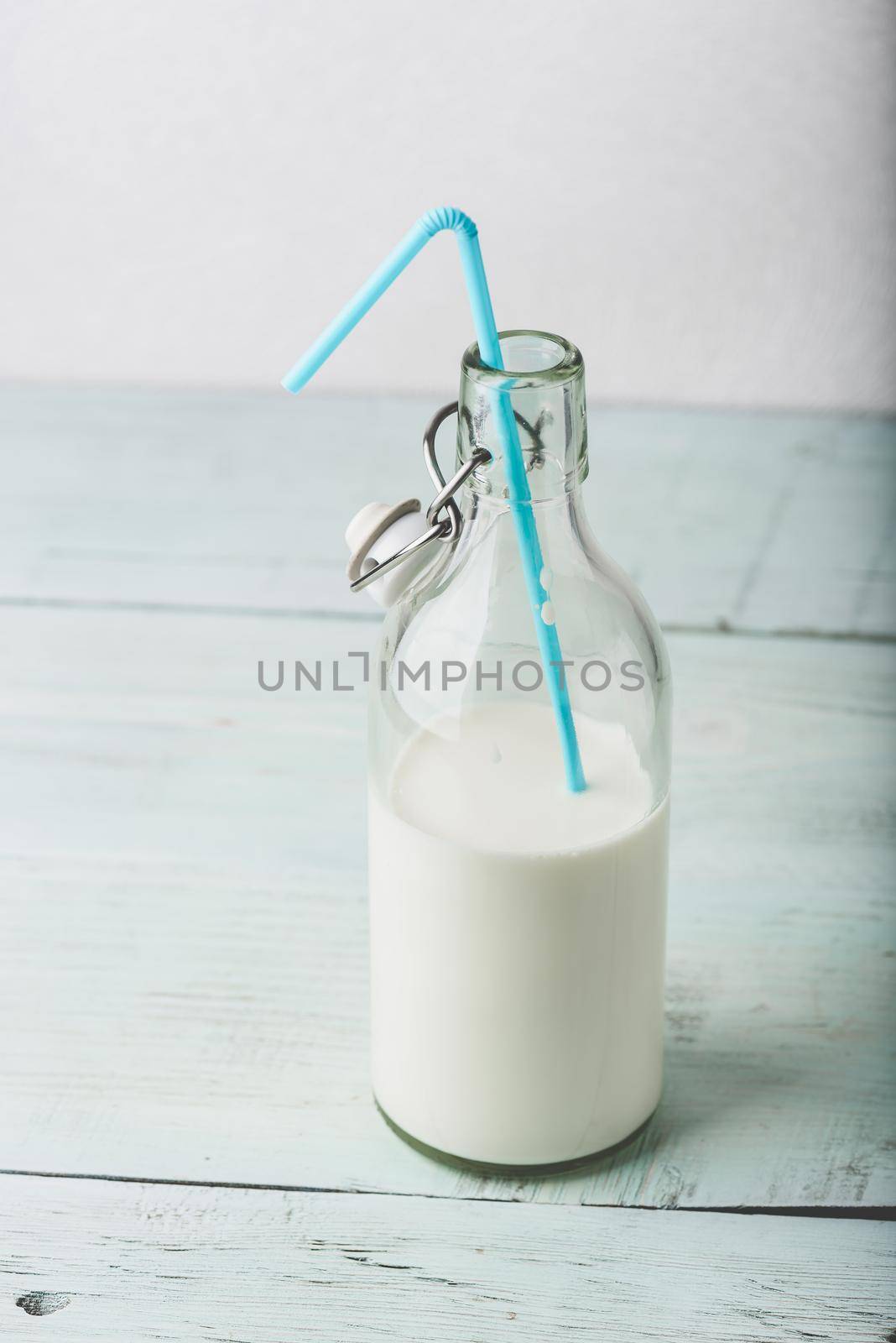 Glass bottle of milk with blue straw