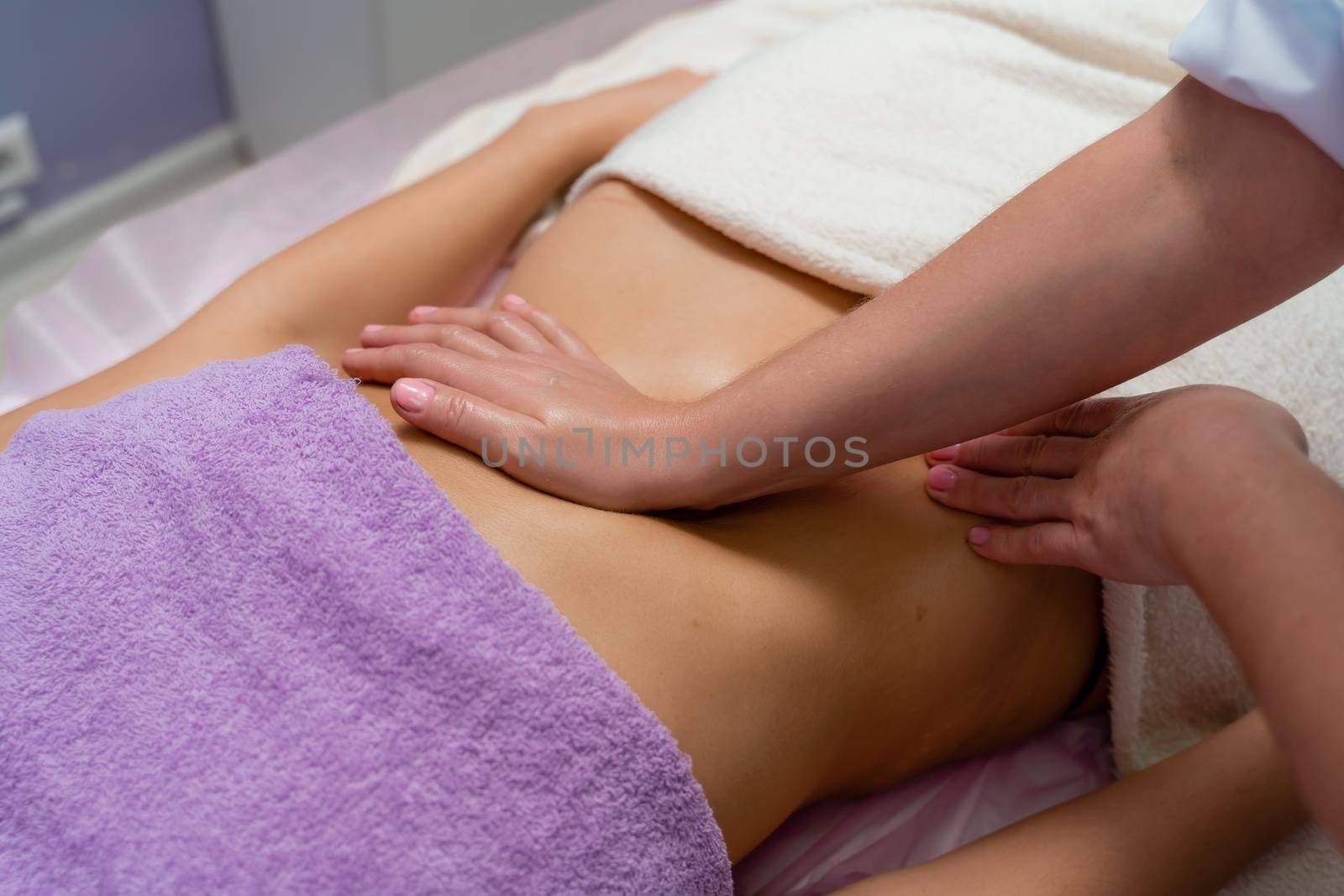 Top view of hands massaging female abdomen.Therapist applying pressure on belly. Woman receiving massage at spa salon by Matiunina