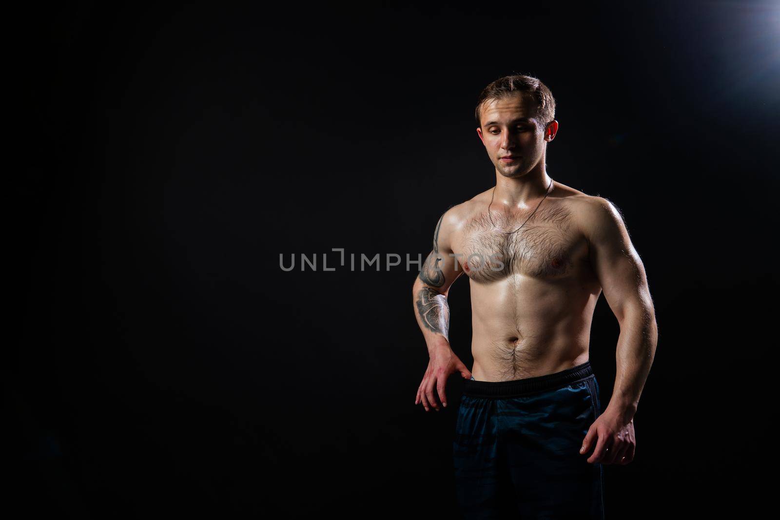 Man on black background keeps dumbbells pumped up in fitness muscle black, athlete strong lifting heavy, shirtless pectoral. Young adult, human fit Look at the press and measures the size of pants for weight loss