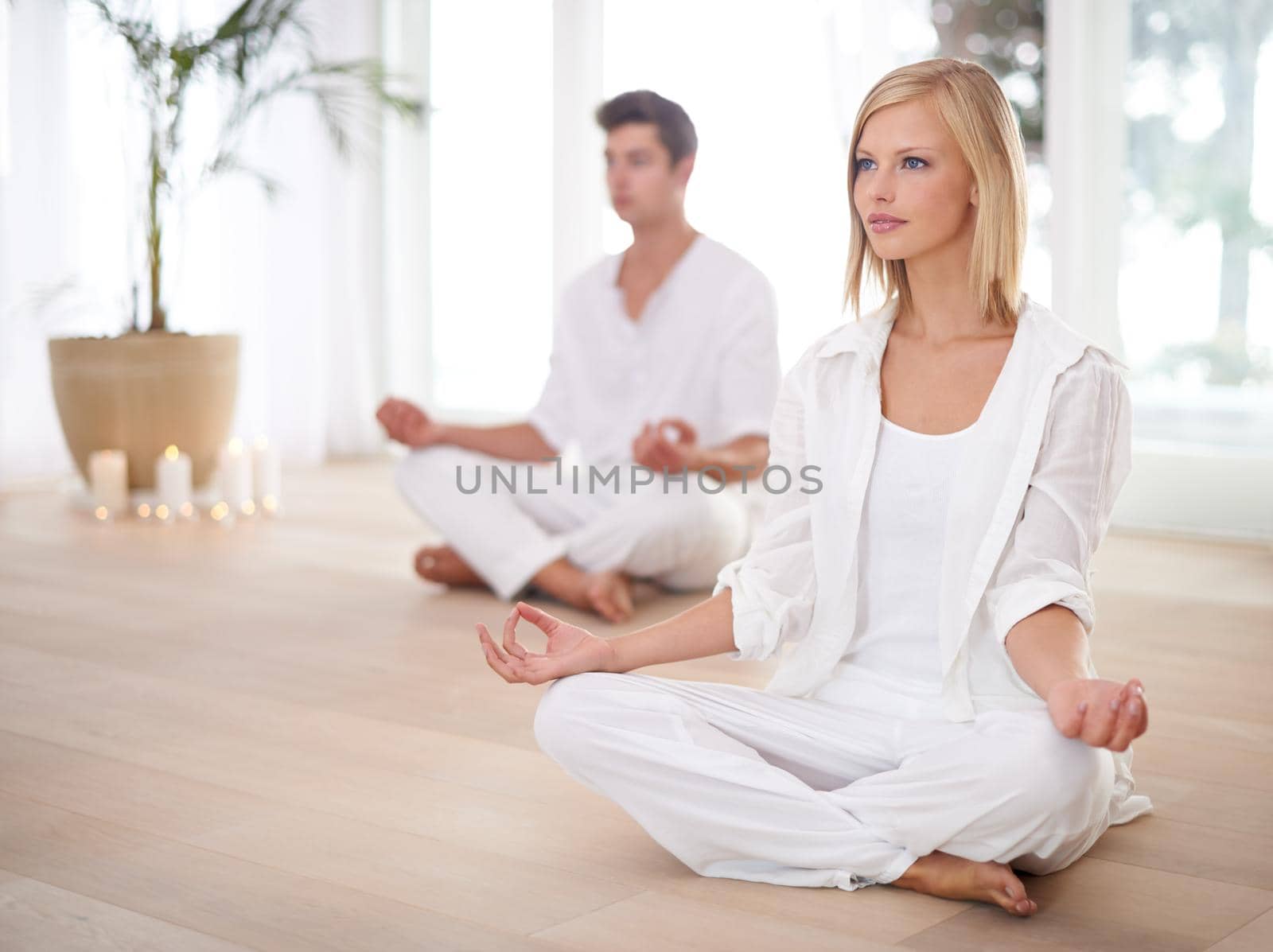 Finding inner peace together. Two people sitting in the lotus position in a yoga studio. by YuriArcurs