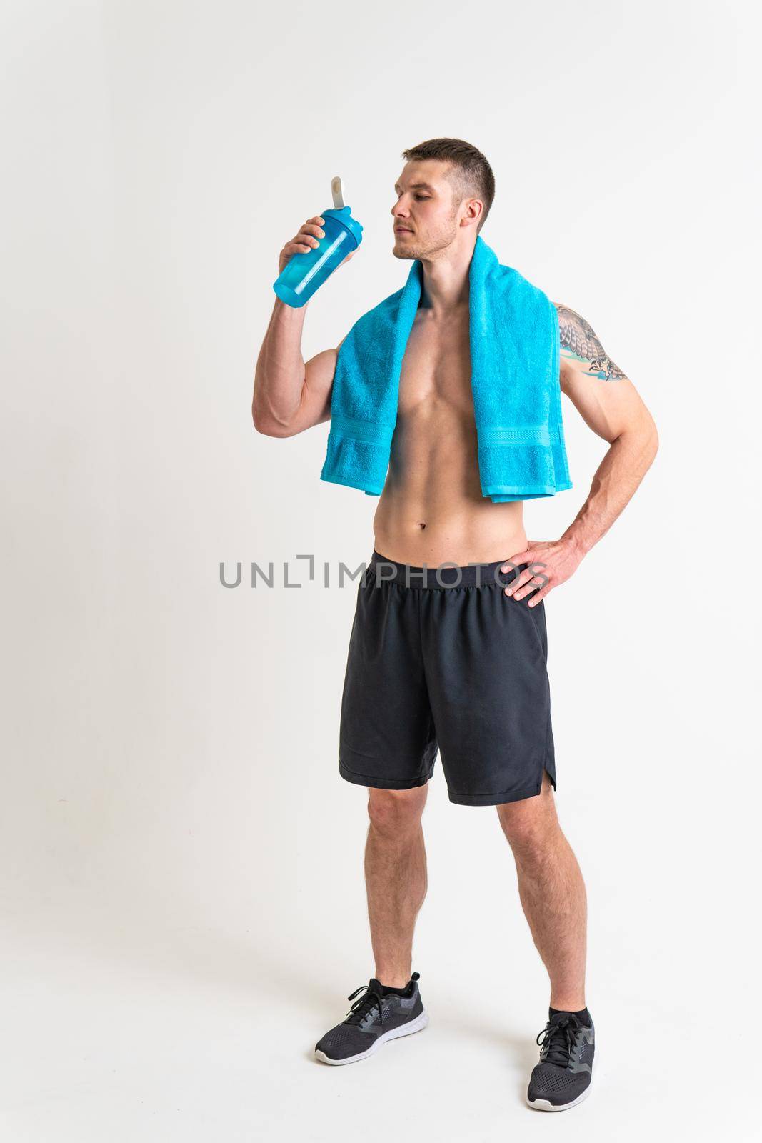 Male drink-water fitness is pumped with a towel on a white background isolated fitness lifestyle, water healthy male bottle holding, muscles cardio. Strength copy tired one muscle