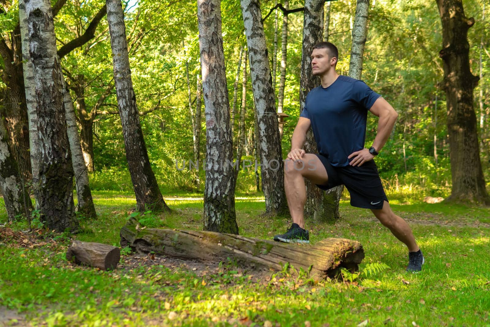 A young enduring athletic athlete is doing stretching in the forest outdoors, around the forest, oak trees. sport forest, lifestyle young legs jog, jogging body cross, stretching stretches