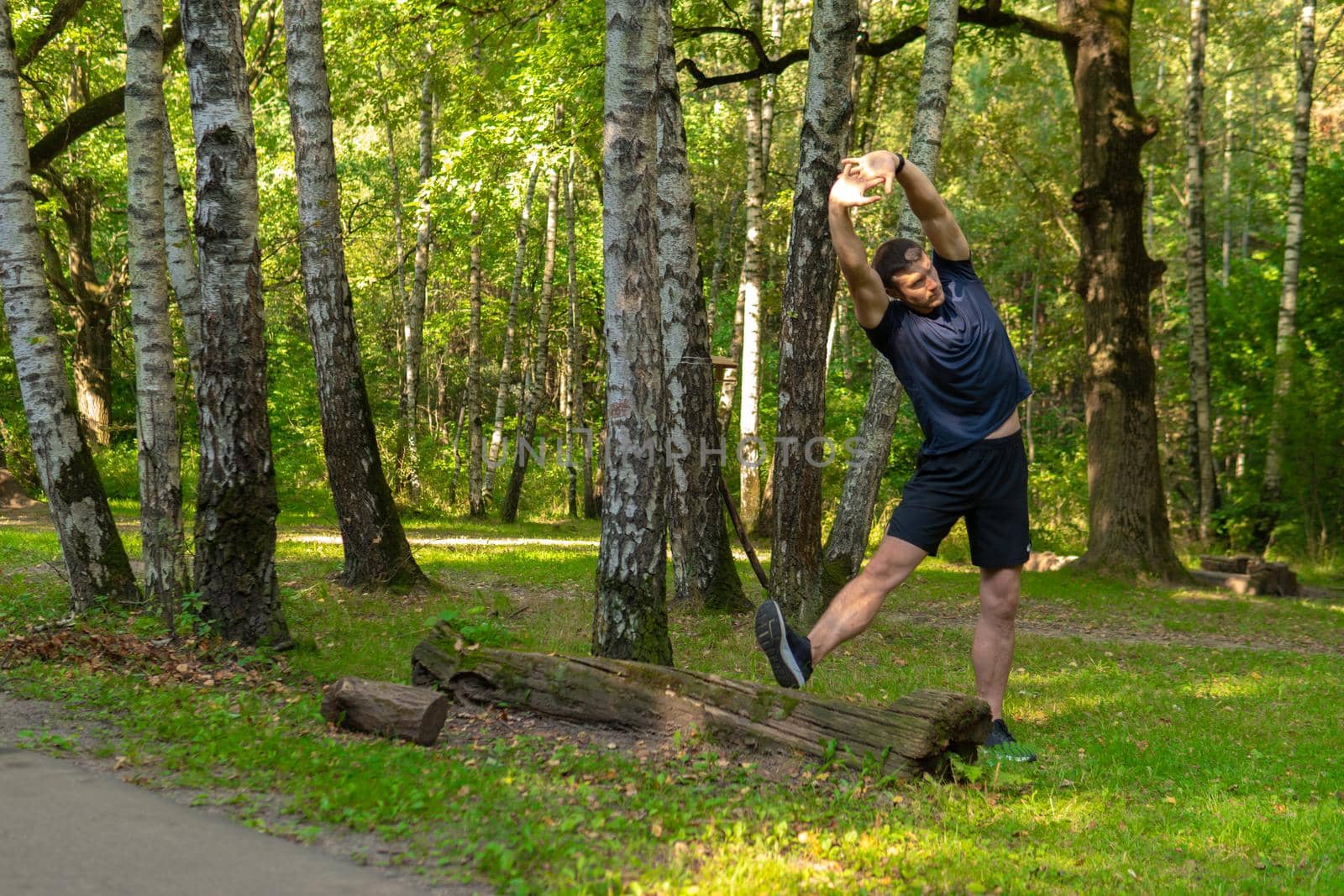 A young enduring athletic athlete is doing stretching in the forest outdoors, around the forest, oak trees.active athlete forest, fitness trail fit recreation woods Summer body running, runners stretches