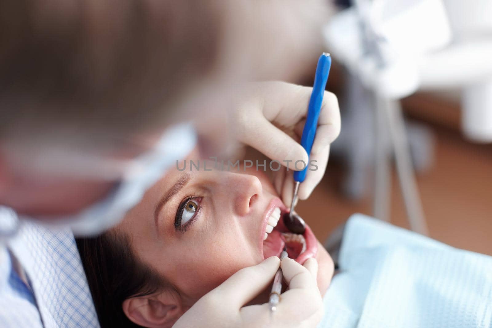 High angle view of dentist checking patients teeth.