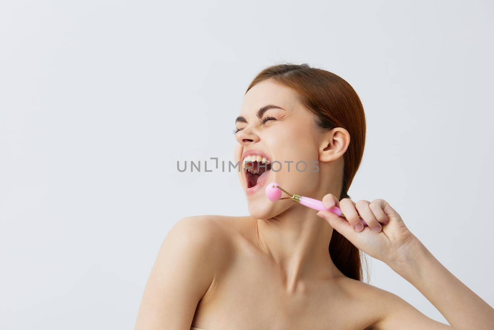 portrait woman pink quartz roller skin care massage bare shoulders close-up Lifestyle. High quality photo