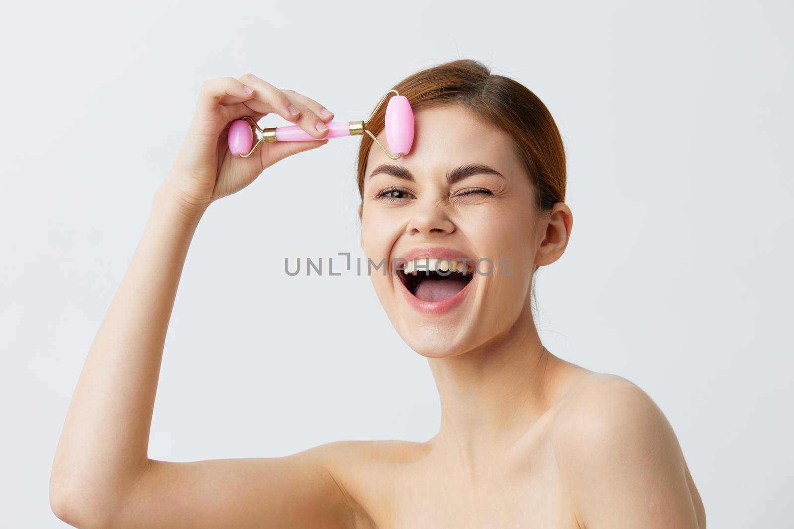 woman massage roller anti aging facial treatment light background. High quality photo