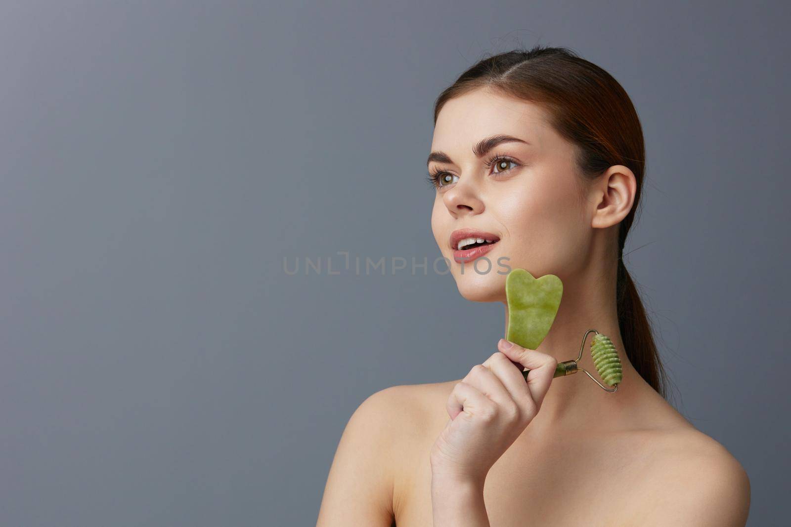 beautiful woman jade face massager wrinkle smoothing isolated background by SHOTPRIME