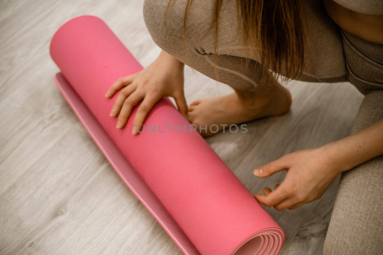 Yoga at home woman rolls pink exercise mat in living room starting to warm up meditation zen well being lifestyle living room apartment