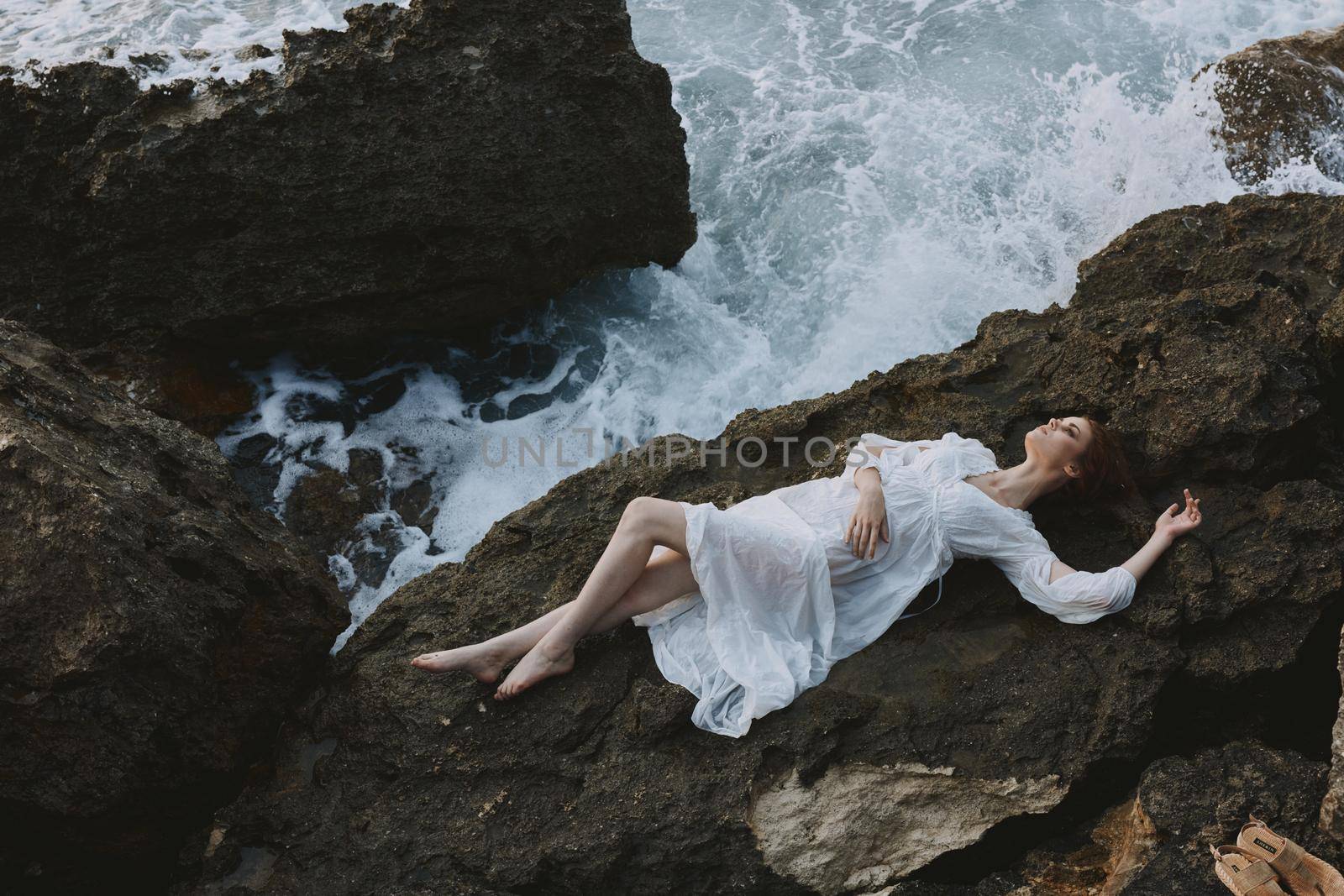 beautiful woman in a secluded spot on a wild rocky coast in a white dress unaltered by SHOTPRIME
