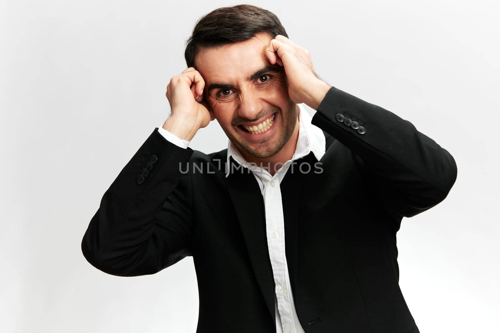 a man with a headache grinds his teeth emotions nervous breakdown at work white studio background, copy space. High quality photo