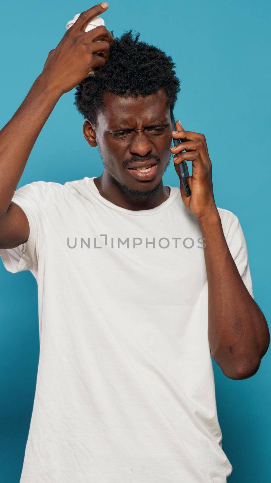 Black person using smartphone for phone call in studio. African american man answering call and feeling worried about news. Frustrated adult using phone for remote communication