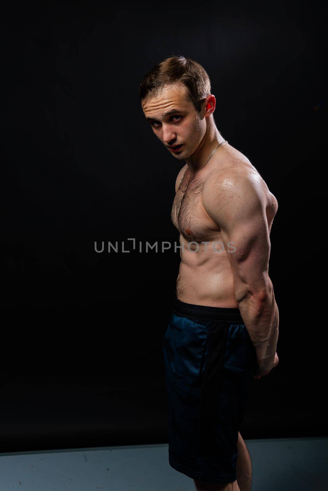 Man on black background keeps dumbbells pumped up in fitness biceps black, weight hold dumbbell, male handsome people fit hands behind your back, press tense beautiful body