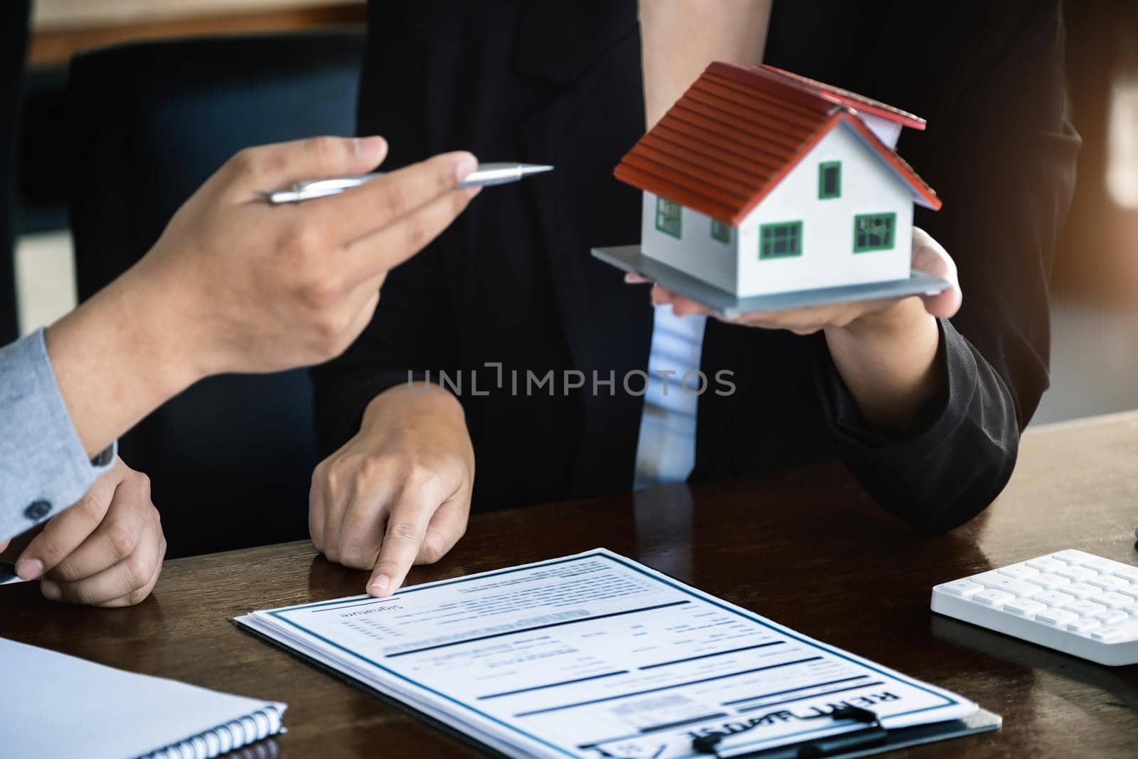Loan signing concept, refinancing, home and land purchase, rental accommodation, female real estate agent or bank employee pointing to a contract or agreement with a male client to to Buy a dwelling. by Manastrong