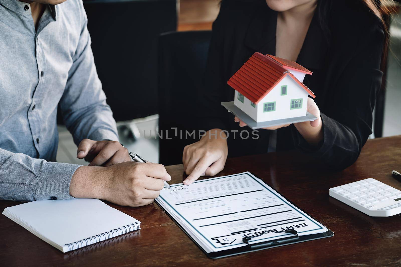 Concept of signing loan, refinancing, buying house and land,rental accommodation, male client signing contract with female real estate agent to Buy a dwelling