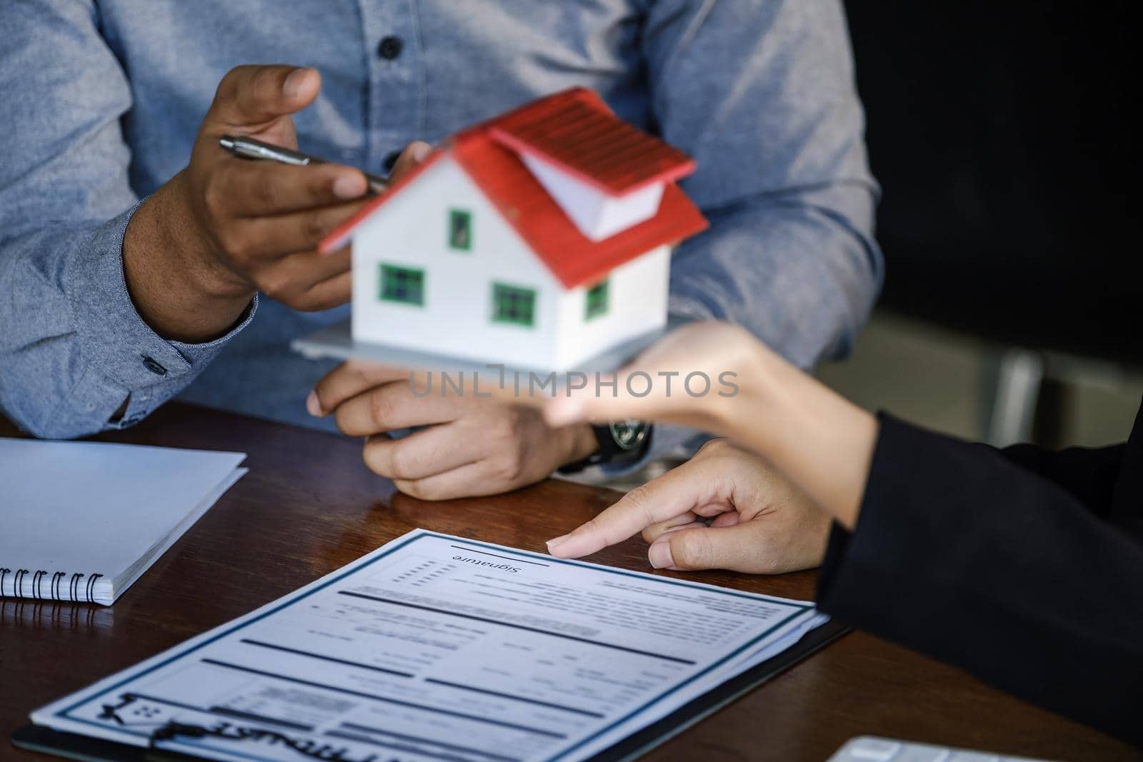 Loan signing concept, refinancing, home and land purchase, rental accommodation, female real estate agent or bank employee pointing to a contract or agreement with a male client to to Buy a dwelling