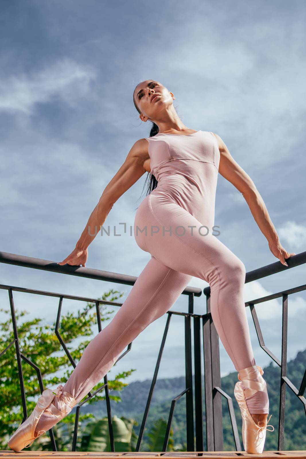 Young fit ballerina in pink pointes stretching, dancing on toes in warm sunrays by XGroup