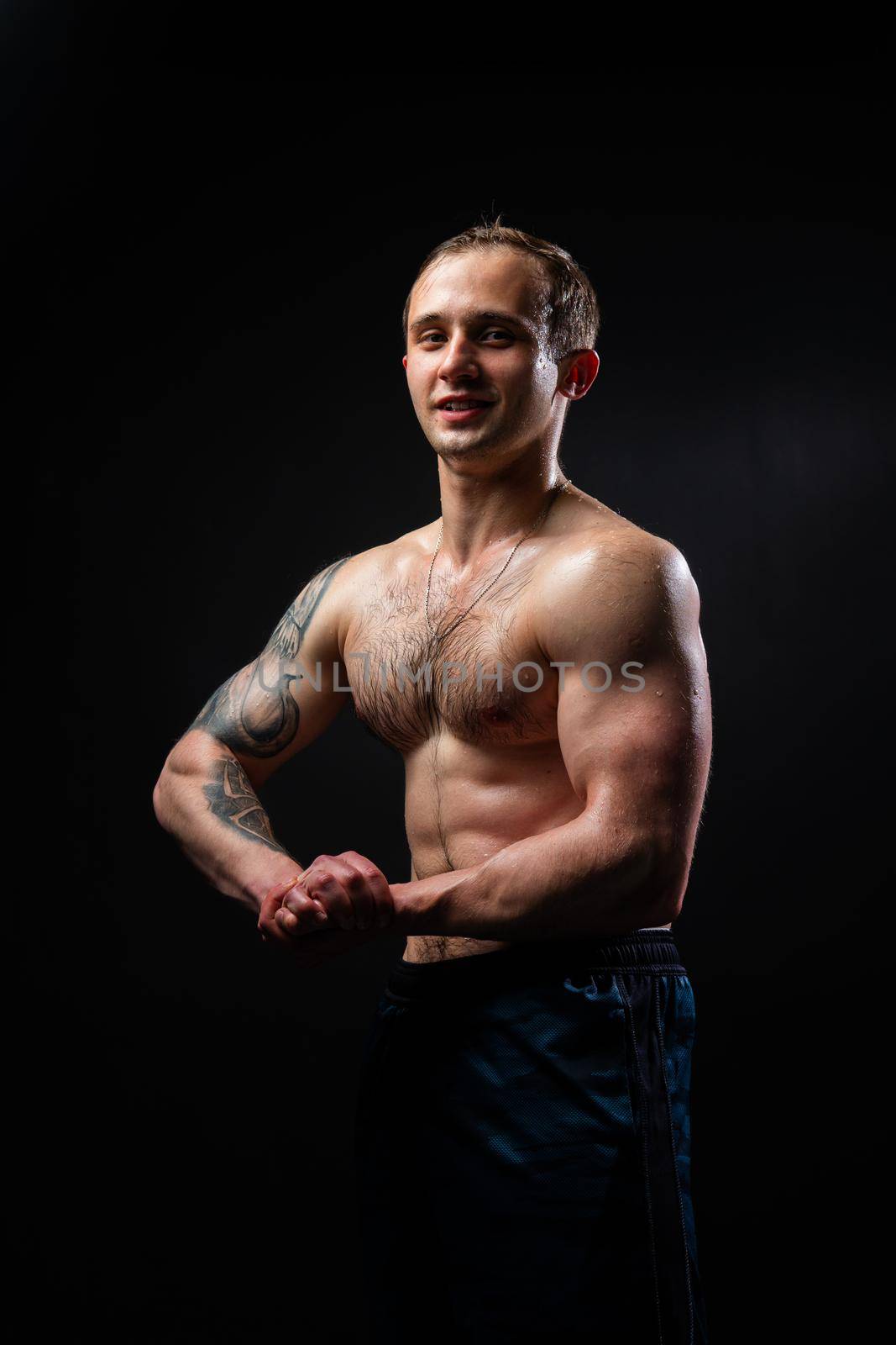 Man on black background keeps dumbbells pumped up in fitness biceps black, body muscular man lifting dumbbell, shirtless Attractive handsome guy fit View from the bottom up good press beautiful muscles hairy chest charisma