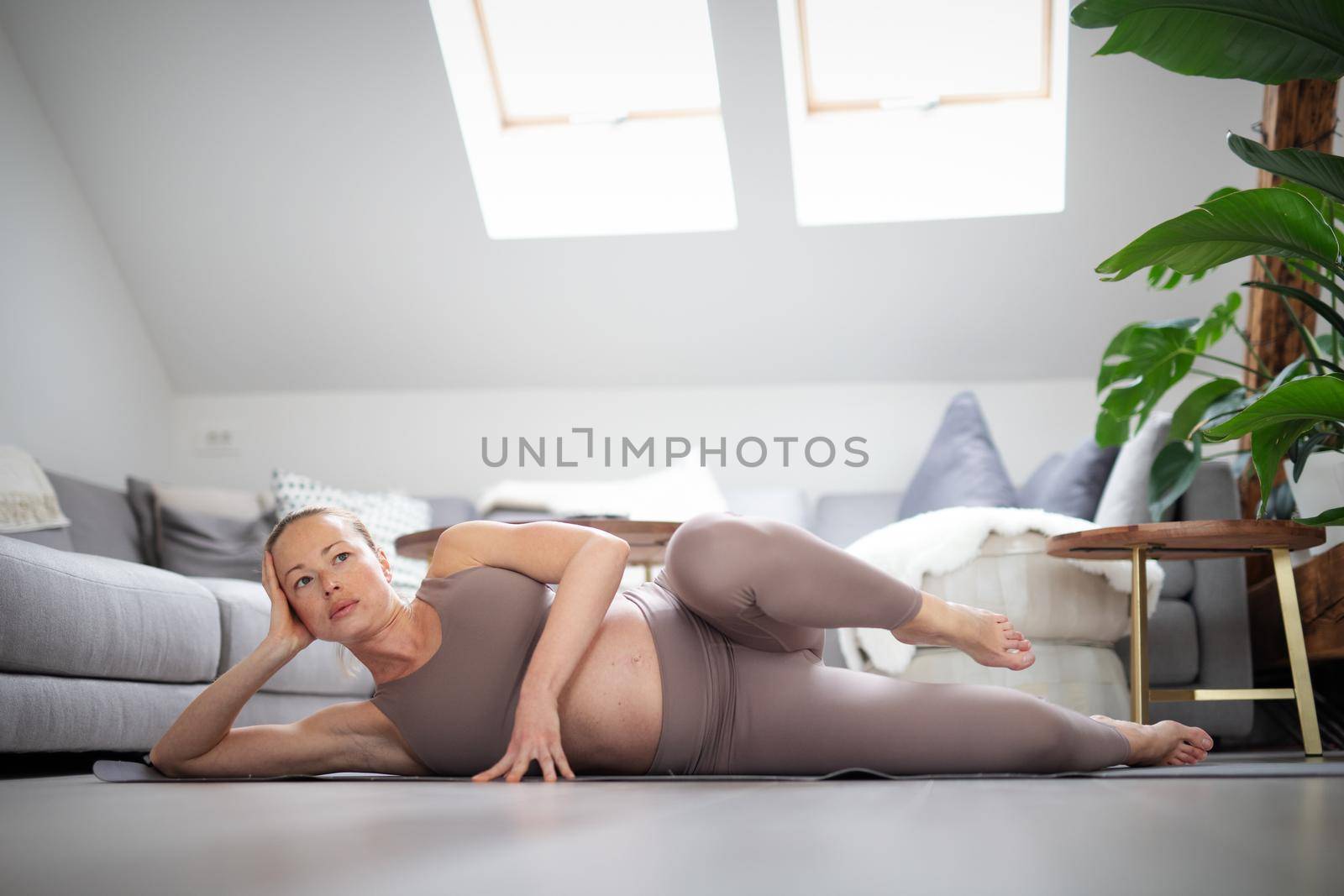 Young beautiful pregnant woman training pilates at home in her living room. Healthy lifestyle and active pregnancy and motherhood concept. by kasto